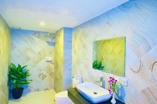 a bathroom with a sink and a toilet and a mirror at Holy Angkor Hotel in Siem Reap