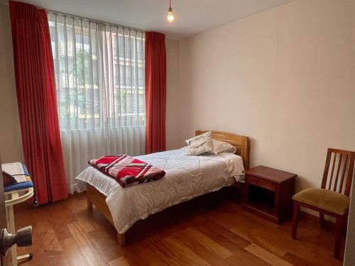 a bedroom with a bed and a window with red curtains at Sisters- Apartamento cómodo y familiar in Cochabamba