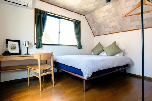 a bedroom with a bed and a chair and a window at Ikken House in Tokyo