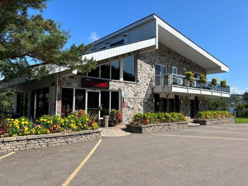 a building with flowers in a parking lot at Motel Panoramique in Saguenay