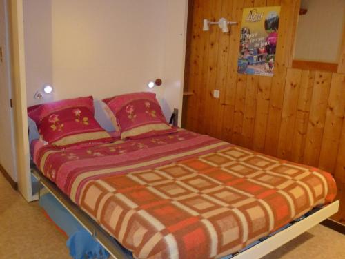 - une chambre dotée d'un lit avec des couvertures rouges et oranges dans l'établissement Studio cosy aux Gets, près des pistes et du centre, avec balcon, garage, Wi-Fi, et espace vélo - FR-1-671-34, aux Gets