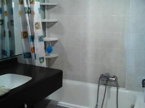 une salle de bain avec une baignoire, un lavabo et une douche dans l'établissement Studio cosy aux Gets, près des pistes et du centre, avec balcon, garage, Wi-Fi, et espace vélo - FR-1-671-34, aux Gets