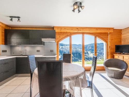 une cuisine avec une table et des chaises ainsi qu'une grande fenêtre dans l'établissement Charmant appartement: 1 ch, parking, WiFi, animaux admis - FR-1-671-13, aux Gets