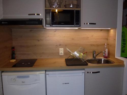 un comptoir de cuisine avec un évier et un micro-ondes dans l'établissement Studio cosy aux Gets, près des pistes et du centre, avec balcon, garage, Wi-Fi, et espace vélo - FR-1-671-34, aux Gets
