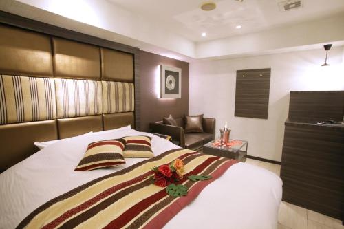 a bedroom with a large bed and a chair at ホテルコスタリゾート飯能 in Hannō