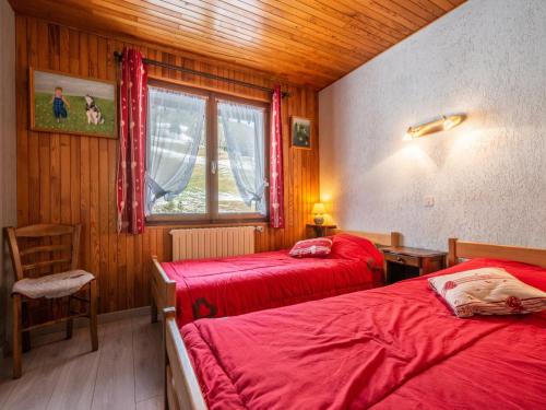 - une chambre avec 2 lits rouges et une fenêtre dans l'établissement Appartement cosy aux Gets - 4 pers, balcon, proche pistes et toutes commodités - FR-1-671-27, aux Gets