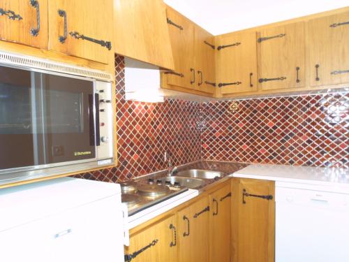 La cuisine est équipée de placards en bois, d'un évier et d'un four micro-ondes. dans l'établissement Appartement familial avec balcon, proche télécabines et centre, garage, animaux admis - Les Gets - FR-1-671-41, aux Gets