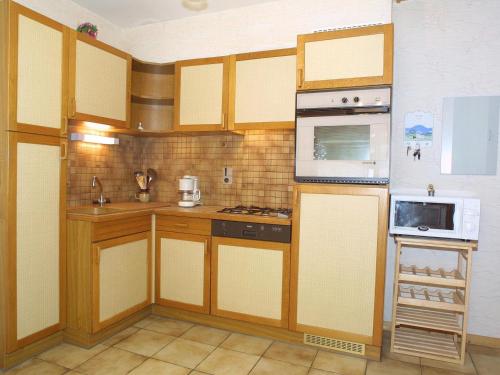 une cuisine avec des armoires en bois et un four à plaques de cuisson dans l'établissement Charmant Appartement Mezzanine 61m², 6 Pers, Proche Centre et Télécabine - Les Gets - FR-1-671-81, aux Gets