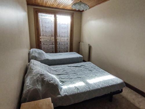 deux lits dans une petite pièce avec une fenêtre dans l'établissement Appartement cosy aux Gets - Idéal famille - Proche pistes - Animaux admis - FR-1-671-74, aux Gets