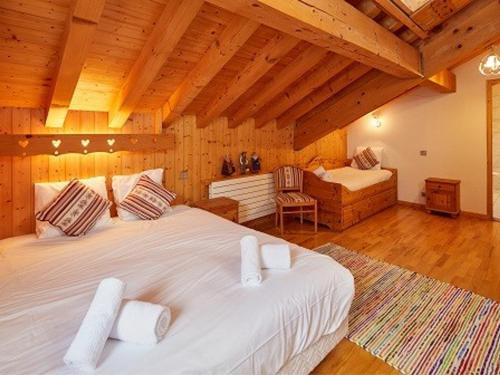 una camera con un grande letto bianco in una stanza con soffitti in legno di Chalet luxueux avec jacuzzi, sauna et WiFi aux Gets - FR-1-671-83 a Les Gets