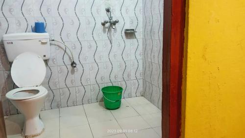 a bathroom with a toilet and a green bucket at Hotel Butterfly - Peaceful Garden for Nature Lovers in Sauraha