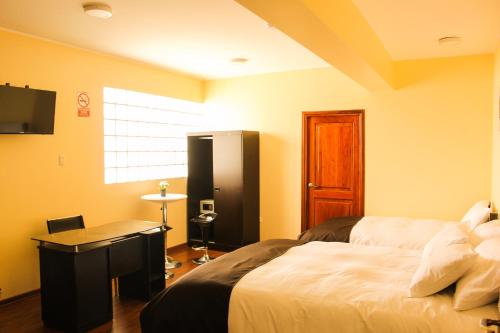a bedroom with a bed and a desk and a window at Hotel B&V in Huancayo