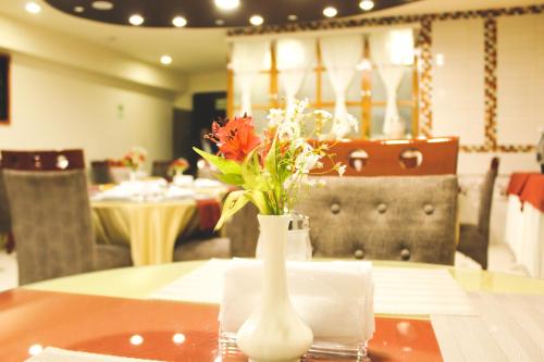 a white vase with flowers sitting on a table at Hotel B&V in Huancayo