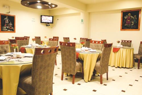 a dining room with tables and chairs and a tv at Hotel B&V in Huancayo