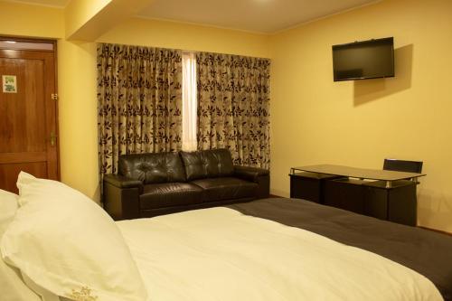 a bedroom with a bed and a couch and a television at Hotel B&V in Huancayo