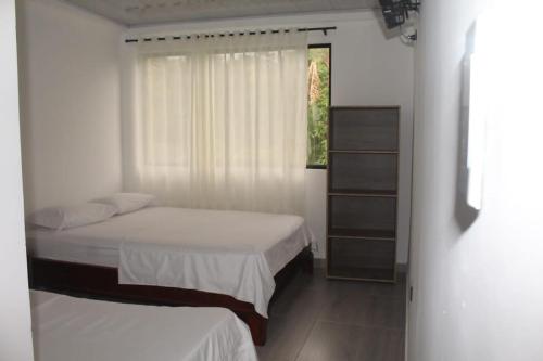 1 dormitorio con 2 camas y ventana en HOTEL EL RUBY, en San Martín