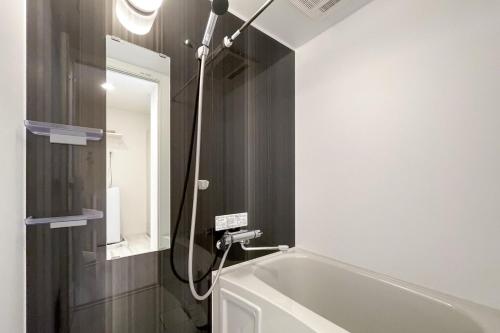a bathroom with a bath tub and a mirror at TASUKI smart Higashishinjuku in Tokyo
