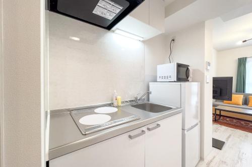 a kitchen with a sink and a refrigerator at TASUKI smart Higashishinjuku in Tokyo