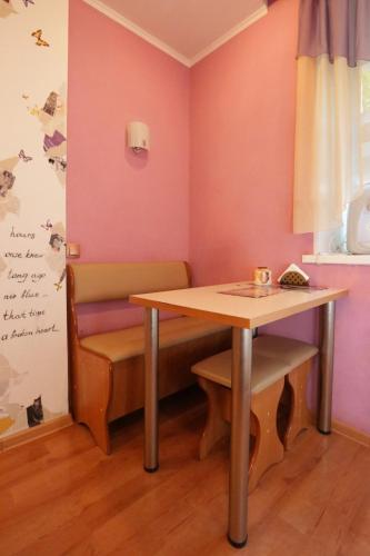 a table and a bench in a room with pink walls at LONDON in Petropavlovsk