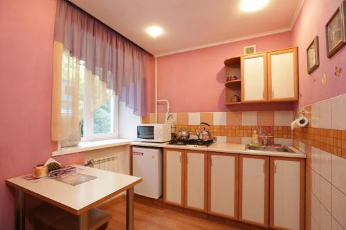 małą kuchnię z różowymi ścianami i stołem w obiekcie LONDON w mieście Pietropawłowsk Kamczacki