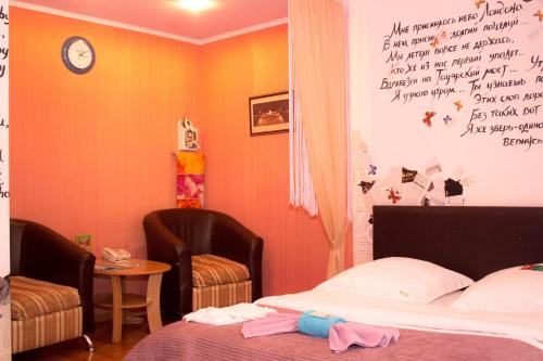 a bedroom with a bed and two chairs and a wall with writing at LONDON in Petropavlovsk