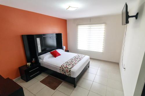 - une chambre avec un lit et un mur rouge dans l'établissement Un espacio privado y cómodo. Casa Nahil., à Jalisco