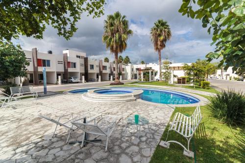 une cour avec une piscine, des chaises et des palmiers dans l'établissement Un espacio privado y cómodo. Casa Nahil., à Jalisco
