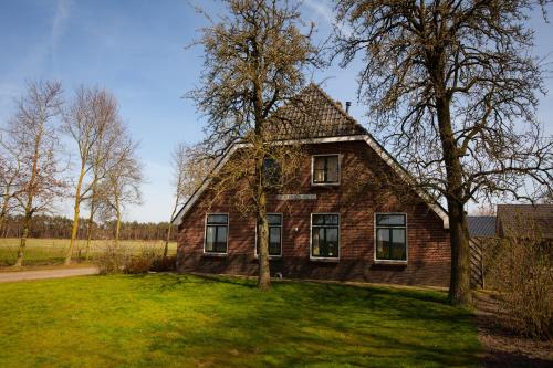 an old brick house with a tree in the yard at Bed And Breakfast Geertruidahoeve in Hellendoorn