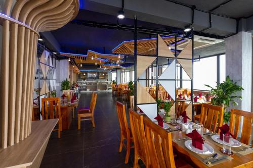 a restaurant with wooden tables and chairs in a room at Pearl Beach Hotel Quy Nhon in Quy Nhon