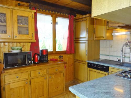 - une cuisine avec des placards en bois et un four micro-ondes dans l'établissement Chalet spacieux aux Gets avec cheminée, WiFi et animaux admis - FR-1-671-128, aux Gets
