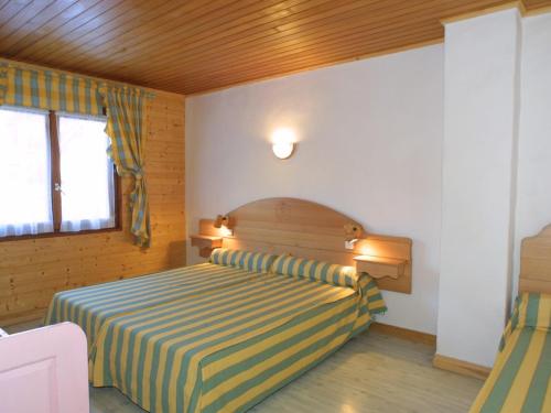 een slaapkamer met een bed met een gestreepte deken bij Appartement Les Gets, 3 pièces, 5 personnes - FR-1-671-231 in Les Gets