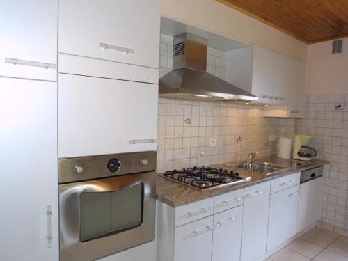 une cuisine avec des armoires blanches et un four à plaques de cuisson dans l'établissement Appartement cosy aux Gets avec Wi-Fi et parking privé - FR-1-671-97, aux Gets
