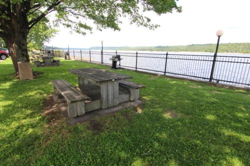 a picnic table sitting in the grass next to a fence at Motel Panoramique in Saguenay