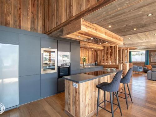 - une cuisine avec des murs en bois et un bar avec des tabourets dans l'établissement Chalet de luxe avec jacuzzi, Wi-Fi et parking privé - FR-1-671-138, aux Gets