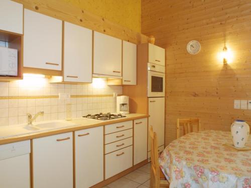 une cuisine avec des armoires blanches, une table et un évier dans l'établissement Charmant appart. familial avec Wi-Fi, proche ski et centre des Gets, terrasse, garage, animaux admis - FR-1-671-148, aux Gets