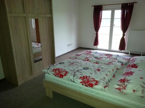 a bedroom with a bed with a flowery comforter and a window at Guest House Starý Sedloňov in Trutnov