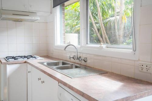 a white kitchen with a sink and a window at 'Bay Beauty' Clifton Springs Family Hideaway in Clifton Springs