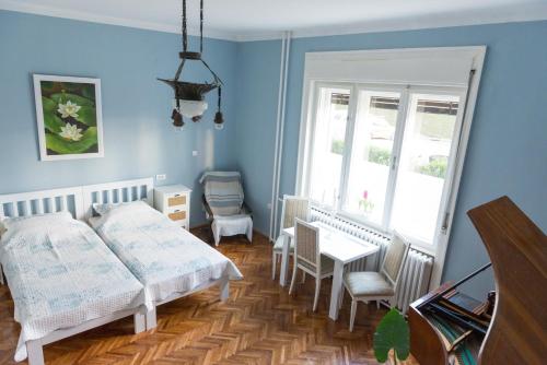 a bedroom with two beds and a table and a window at Apartments Girasole in Novi Sad
