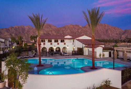 una piscina con palmeras frente a una casa en PGA West -3 bdrm house w/Bonus Loft, Sleeps 8, Pool, Gym en La Quinta