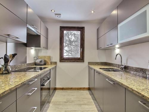 d'une cuisine équipée d'appareils en acier inoxydable et d'une fenêtre. dans l'établissement Chalet rénové au pied des pistes avec balcon et cheminée - FR-1-455-231, à La Plagne Tarentaise