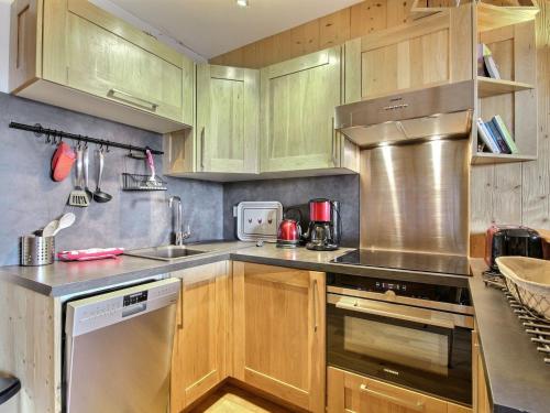 une cuisine avec des armoires en bois et des appareils en acier inoxydable dans l'établissement Duplex moderne au pied des pistes pour 6 personnes - FR-1-455-233, à La Plagne Tarentaise