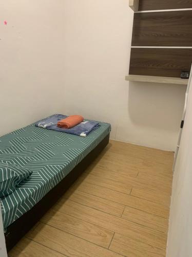 a small bed in a room with a wooden floor at D'Aqiela Homestay @ ITCC in Penampang