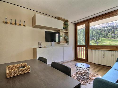 un salon avec une table et une grande fenêtre dans l'établissement Joli studio rénové pour 4, au pied des pistes, balcon, cuisine équipée, non fumeur - FR-1-455-235, à La Plagne Tarentaise