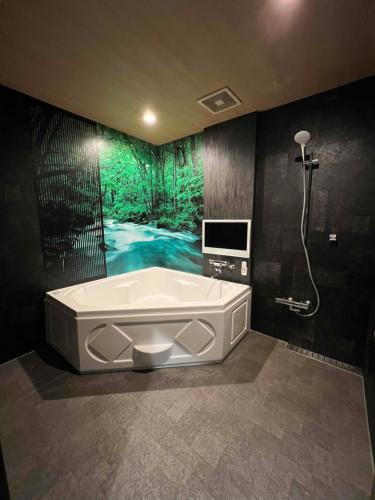 uma casa de banho com uma banheira e um chuveiro e uma televisão em Hotel Park Hill em Sasebo