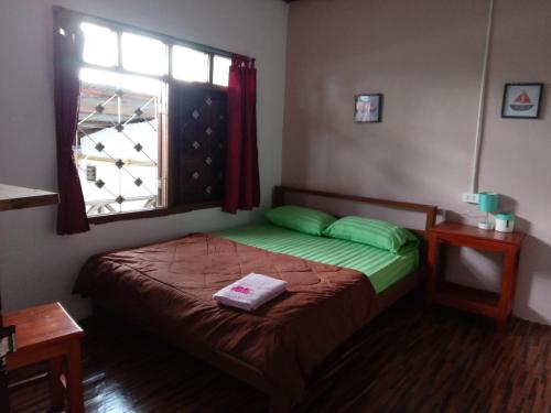 a small bedroom with a bed with a window at Bami hostel in Thakhek