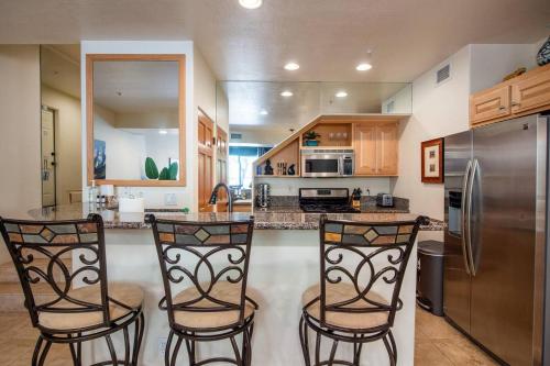 a kitchen with two bar stools and a stainless steel refrigerator at Uptown Sedona Gem: 3-Bed Townhome with Majestic Views and Central Location in Sedona