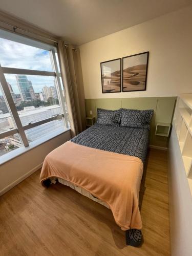 a bedroom with a bed and a large window at Iguatemi Business & Flat in Salvador
