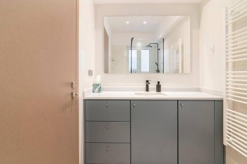 een witte badkamer met een wastafel en een spiegel bij Serenity & Luxury - Elegant 2BR in Kifisia's Center in Athene