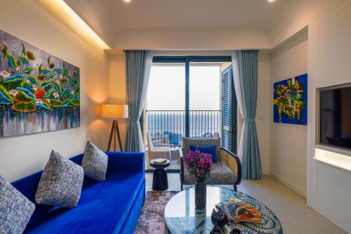 a living room with a blue couch and a glass table at Nexus House Ocean front & Hillside Phú Quốc in Phu Quoc