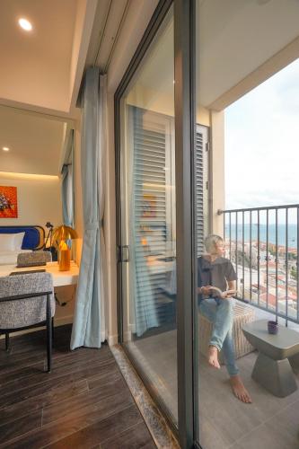 a person sitting on a balcony in a room at Nexus House Ocean front & Hillside Phú Quốc in Phu Quoc